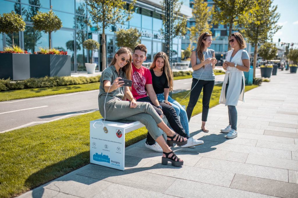 women-sitting-on-solar-bench-taking-selfie